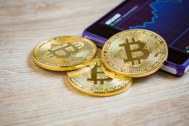 Altın bitcoin ve smartohone ahşap arka plan üzerinde. Cryptocurrency kavramı