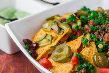 Bir tabak jalapeno, fasulye ve guacamole soslu lezzetli cips 