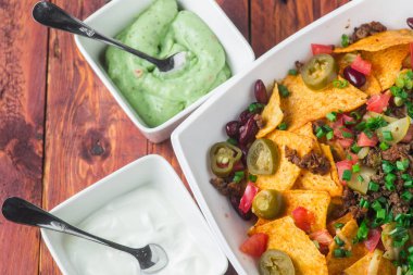 Bir tabak jalapeno, fasulye ve guacamole soslu lezzetli cips 