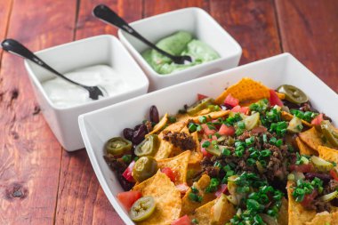 Bir tabak jalapeno, fasulye ve guacamole soslu lezzetli cips 