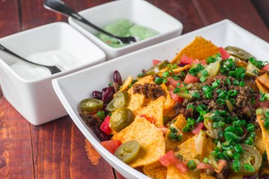 Bir tabak jalapeno, fasulye ve guacamole soslu lezzetli cips 