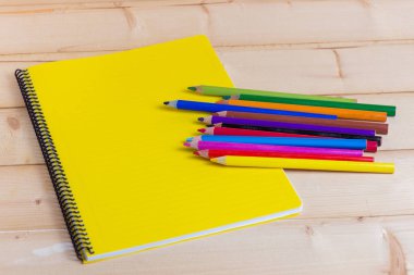 Sarı not defteri ve kalemleri ahşap arka plan üzerinde