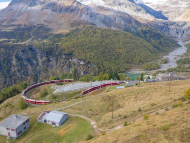 İsviçre 'nin Grisons kentindeki Bernina demiryolu hattı dünyanın en ünlü demiryollarından biridir. Alp Gruem 'e yakın bir virajdan geçen iki kırmızı trenin durumu. 