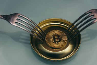 Altın bitcoin ve iki gümüş çatal