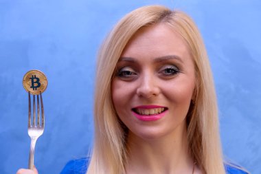 mavi elbiseli güzel bir sarışın kızın elinde altın bitcoin