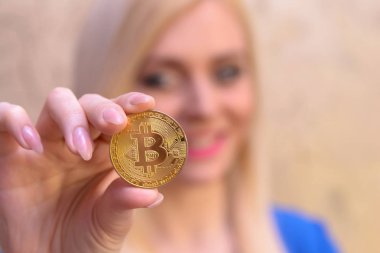 mavi elbiseli güzel bir sarışın kızın elinde altın bitcoin