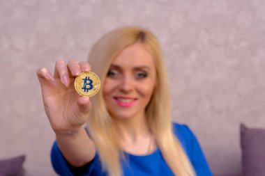 mavi elbiseli güzel bir sarışın kızın elinde altın bitcoin