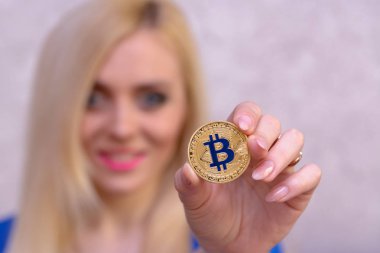 mavi elbiseli güzel bir sarışın kızın elinde altın bitcoin