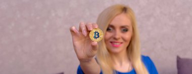 mavi elbiseli güzel bir sarışın kızın elinde altın bitcoin