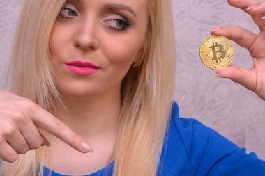 mavi elbiseli güzel bir sarışın kızın elinde altın bitcoin