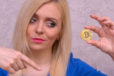 mavi elbiseli güzel bir sarışın kızın elinde altın bitcoin