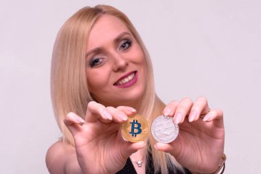 Altın bitcoin ve güzel bir sarışın kızın elinde gümüş litecoin 