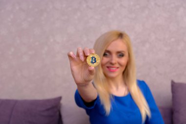 mavi elbiseli güzel bir sarışın kızın elinde altın bitcoin