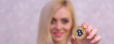 mavi elbiseli güzel bir sarışın kızın elinde altın bitcoin