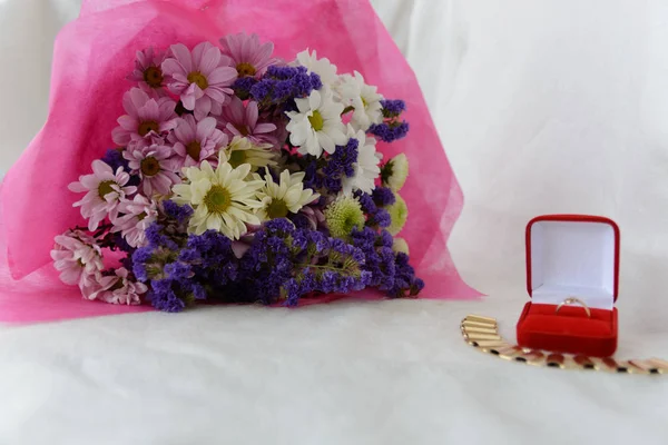 beautiful bouquet of flowers and present box with golden wedding ring