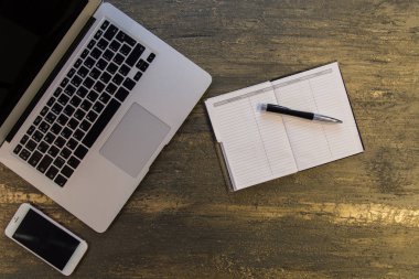 Metin kopyalama yeri olan eski bronz arka plan üzerinde tablo ya da dizüstü bilgisayar, boş defter, kalem ve akıllı telefon Danışma üstten görünüm.