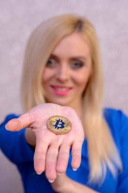 mavi elbiseli güzel bir sarışın kızın elinde altın bitcoin