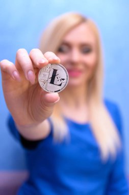 mavi elbiseli güzel bir sarışın kızın elinde gümüş litecoin