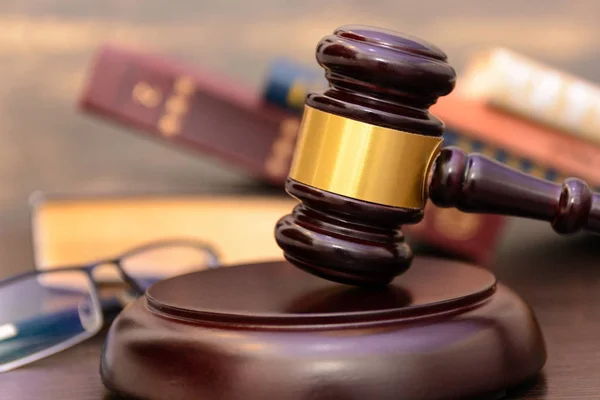 judge gavel beside pile of books on wooden background