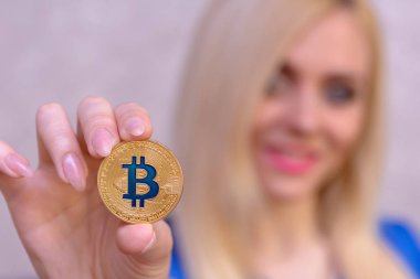 mavi elbiseli güzel bir sarışın kızın elinde altın bitcoin