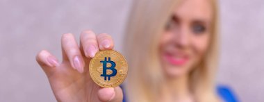 mavi elbiseli güzel bir sarışın kızın elinde altın bitcoin