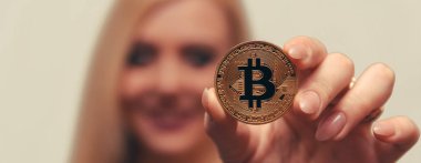 içinde belgili tanımlık geçmiş bulanık bir odak ile güzel bir kızın elinde altın bitcoin