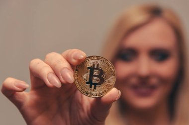 içinde belgili tanımlık geçmiş bulanık bir odak ile güzel bir kızın elinde altın bitcoin