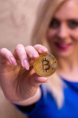 mavi elbiseli güzel bir sarışın kızın elinde altın bitcoin