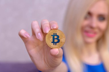 mavi elbiseli güzel bir sarışın kızın elinde altın bitcoin