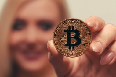 içinde belgili tanımlık geçmiş bulanık bir odak ile güzel bir kızın elinde altın bitcoin