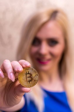 mavi elbiseli güzel bir sarışın kızın elinde altın bitcoin