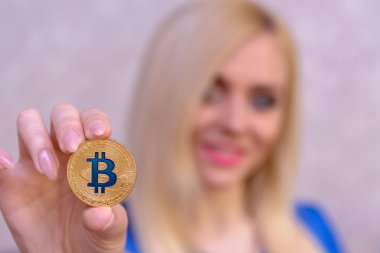 mavi elbiseli güzel bir sarışın kızın elinde altın bitcoin