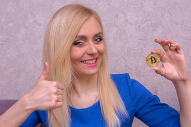 mavi elbiseli güzel bir sarışın kızın elinde altın bitcoin