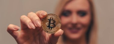 içinde belgili tanımlık geçmiş bulanık bir odak ile güzel bir kızın elinde altın bitcoin