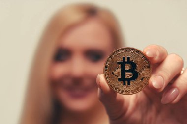 içinde belgili tanımlık geçmiş bulanık bir odak ile güzel bir kızın elinde altın bitcoin