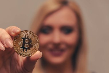 içinde belgili tanımlık geçmiş bulanık bir odak ile güzel bir kızın elinde altın bitcoin