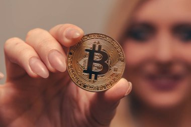 içinde belgili tanımlık geçmiş bulanık bir odak ile güzel bir kızın elinde altın bitcoin