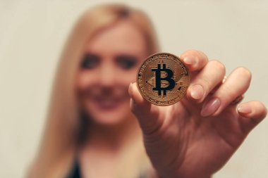 içinde belgili tanımlık geçmiş bulanık bir odak ile güzel bir kızın elinde altın bitcoin