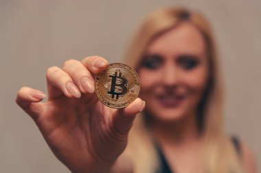 içinde belgili tanımlık geçmiş bulanık bir odak ile güzel bir kızın elinde altın bitcoin