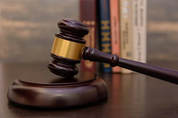 judge gavel beside pile of books on wooden background