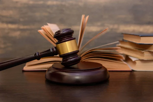 judge gavel beside pile of books on wooden background