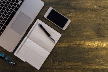 Metin kopyalama yeri olan eski bronz arka plan üzerinde tablo ya da dizüstü bilgisayar, boş defter, kalem ve akıllı telefon Danışma üstten görünüm.