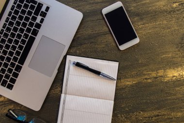 Metin kopyalama yeri olan eski bronz arka plan üzerinde tablo ya da dizüstü bilgisayar, boş defter, kalem, gözlük ve akıllı telefon Danışma üstten görünüm.