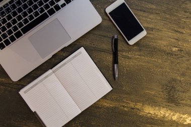 Metin kopyalama yeri olan eski bronz arka plan üzerinde tablo ya da dizüstü bilgisayar, boş defter, kalem ve akıllı telefon Danışma üstten görünüm.