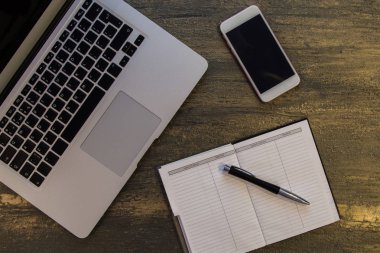 Metin kopyalama yeri olan eski bronz arka plan üzerinde tablo ya da dizüstü bilgisayar, boş defter, kalem ve akıllı telefon Danışma üstten görünüm.