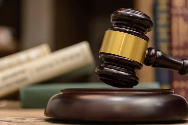 judge gavel beside pile of books on wooden background