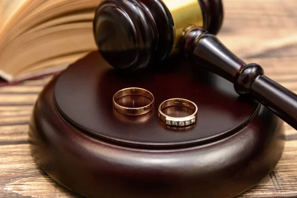 Law and Justice. Judge gavel and wedding rings on wooden background