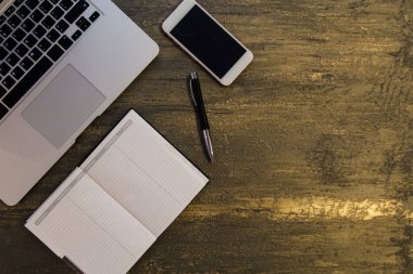 Metin kopyalama yeri olan eski bronz arka plan üzerinde tablo ya da dizüstü bilgisayar, boş defter, kalem ve akıllı telefon Danışma üstten görünüm.