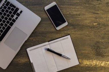 Metin kopyalama yeri olan eski bronz arka plan üzerinde tablo ya da dizüstü bilgisayar, boş defter, kalem ve akıllı telefon Danışma üstten görünüm.