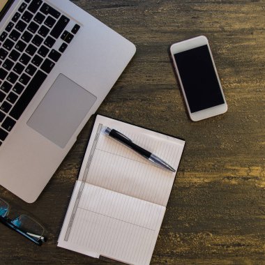 Metin kopyalama yeri olan eski bronz arka plan üzerinde tablo ya da dizüstü bilgisayar, boş defter, kalem, gözlük ve akıllı telefon Danışma üstten görünüm.